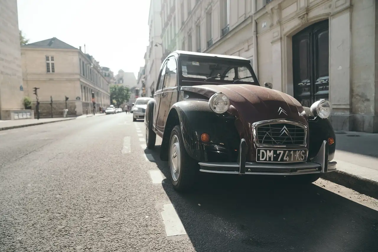 A dark red vintage Citroën 2CV parked on a city street