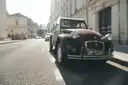 A dark red vintage Citroën 2CV parked on a city street