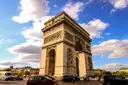 The Arc de Triomphe with traffic circling it under white clouds