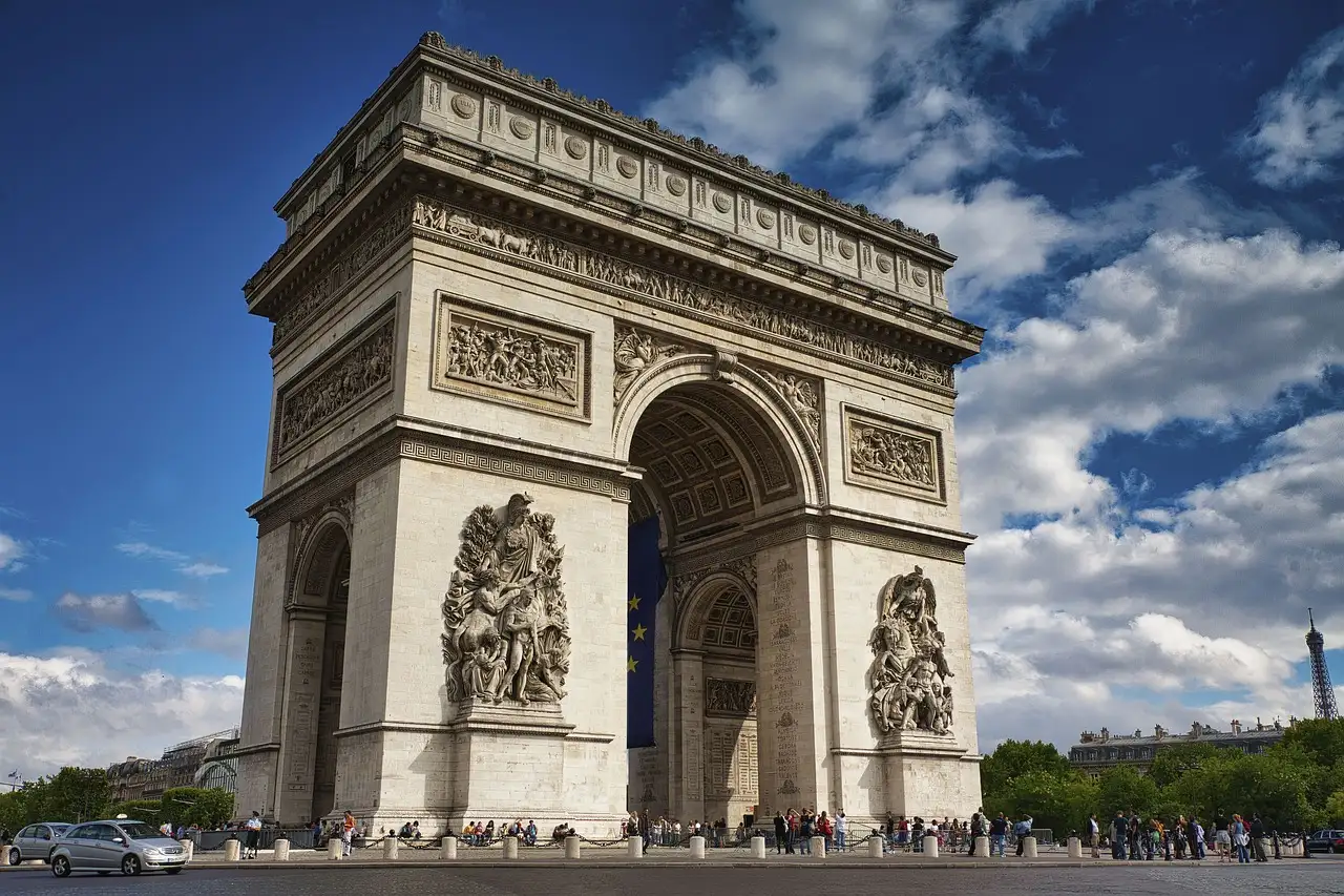 The Arc de Triomphe under a blue sky with white clouds