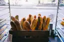 Baguettes standing in a wooden crate in a bakery window