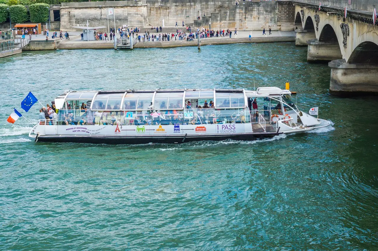 A glass-roofed Batobus river shuttle on the Seine near a bridge