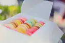 An open paper box filled with pastel macarons