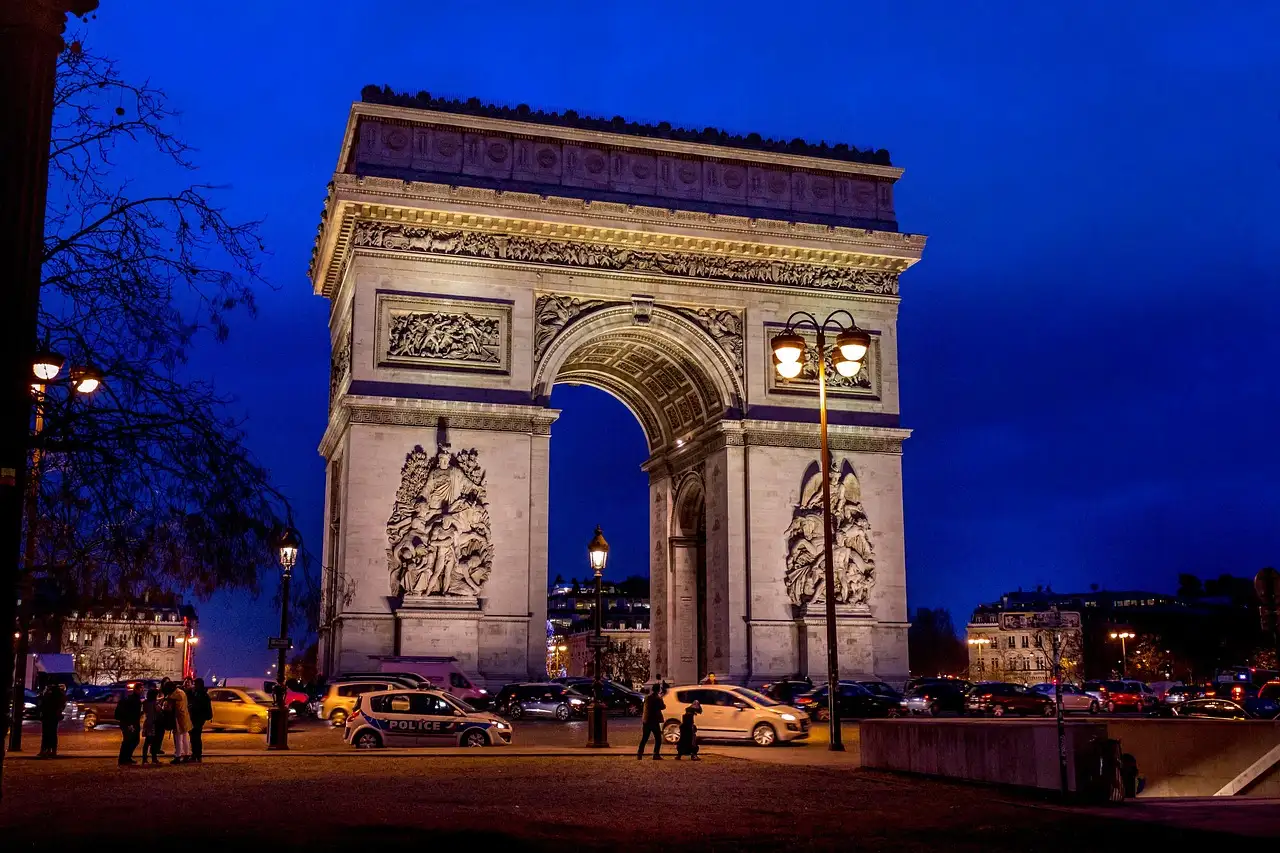 The Arc de Triomphe lit up at dusk against a deep blue sky