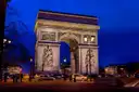 The Arc de Triomphe lit up at dusk against a deep blue sky