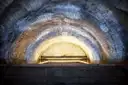 An arched stone tunnel in the Paris Catacombs, softly lit