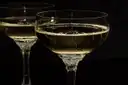 Two coupes of champagne against a dark background