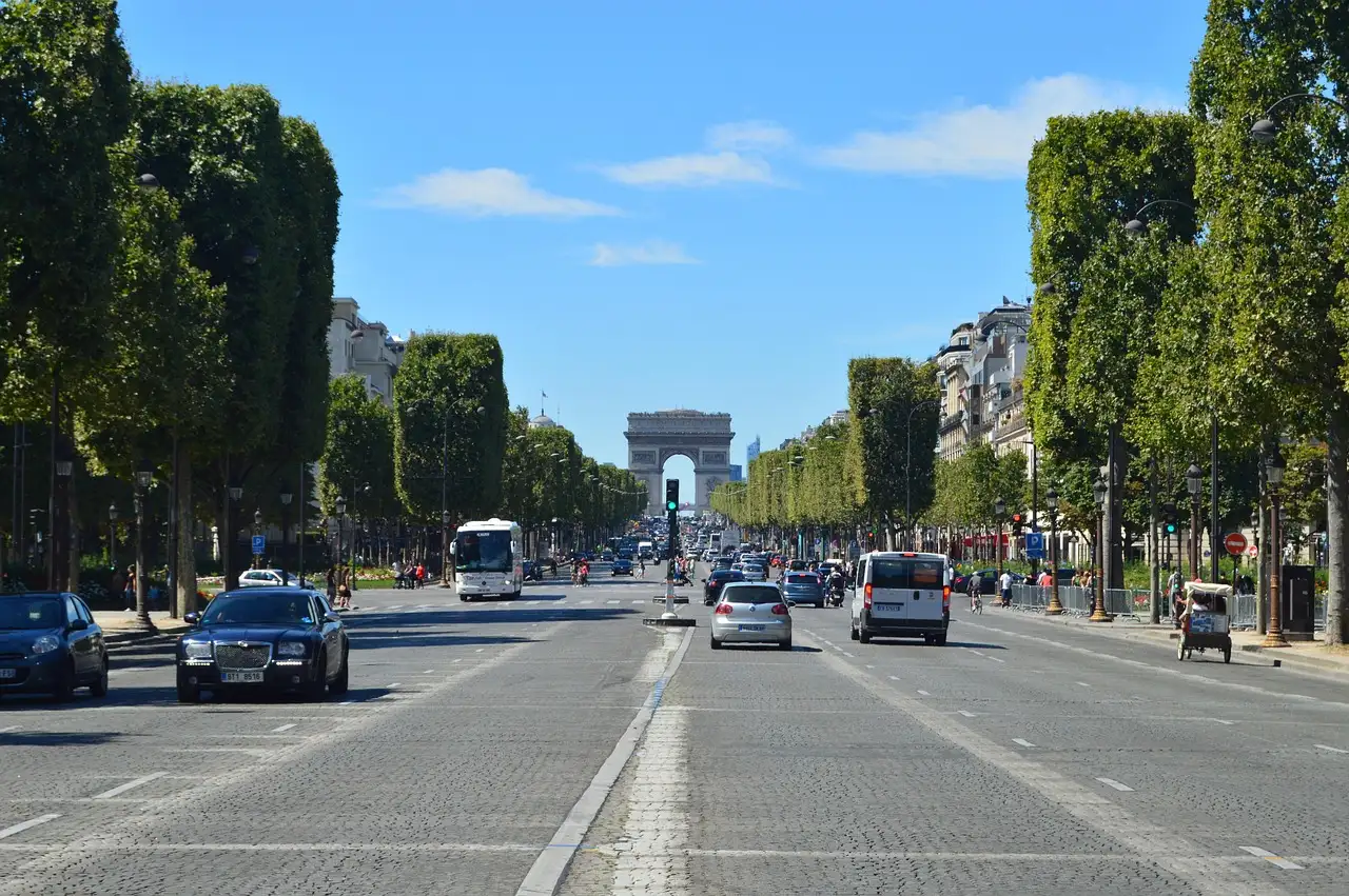 The wide Champs-Élysées on a summer day, the Arc de Triomphe at the far end