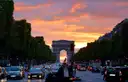 The Arc de Triomphe at the end of the Champs-Élysées under a red sunset sky