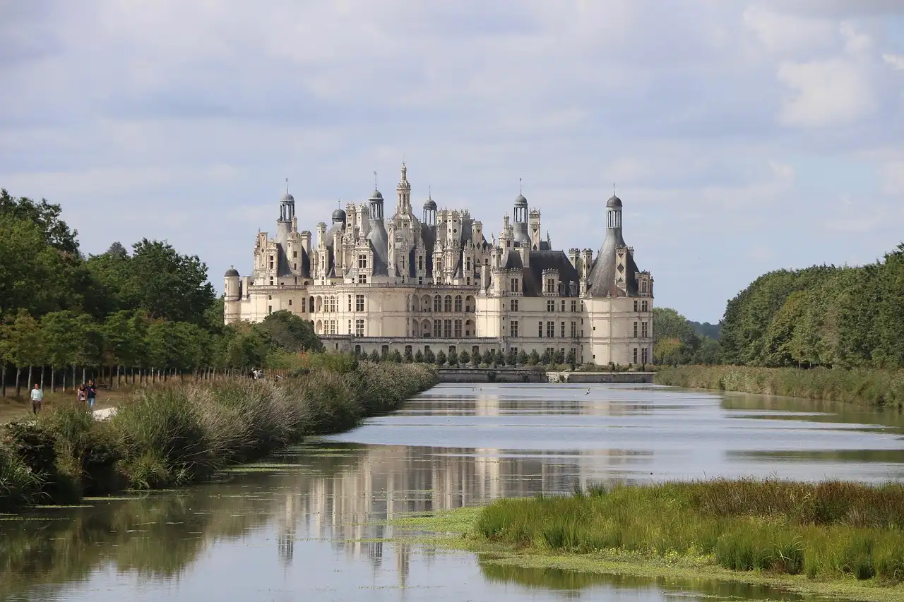 The Château de Chambord seen across a still, reed-lined river
