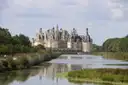 The Château de Chambord seen across a still, reed-lined river