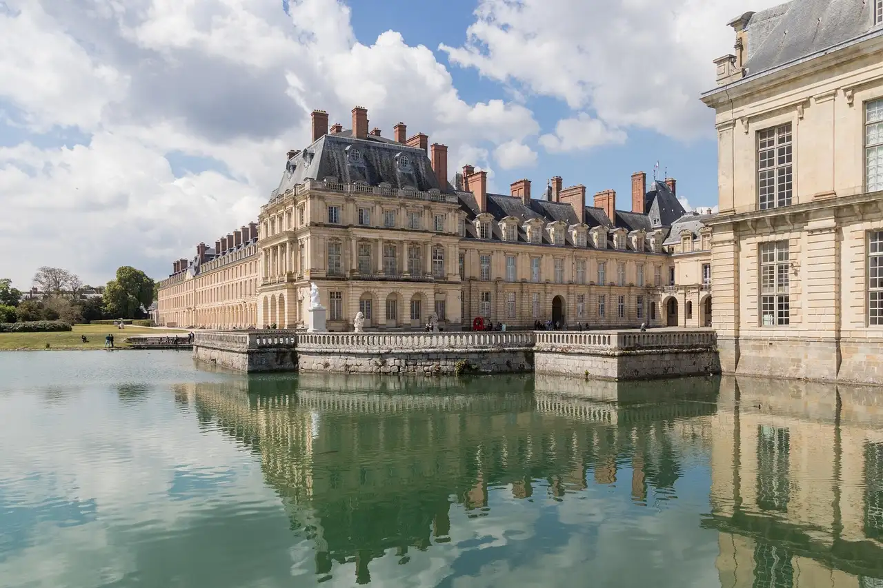 The Château de Fontainebleau reflected in the Carp Pond under white clouds