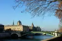 The Conciergerie beyond a Seine bridge on a sunny day