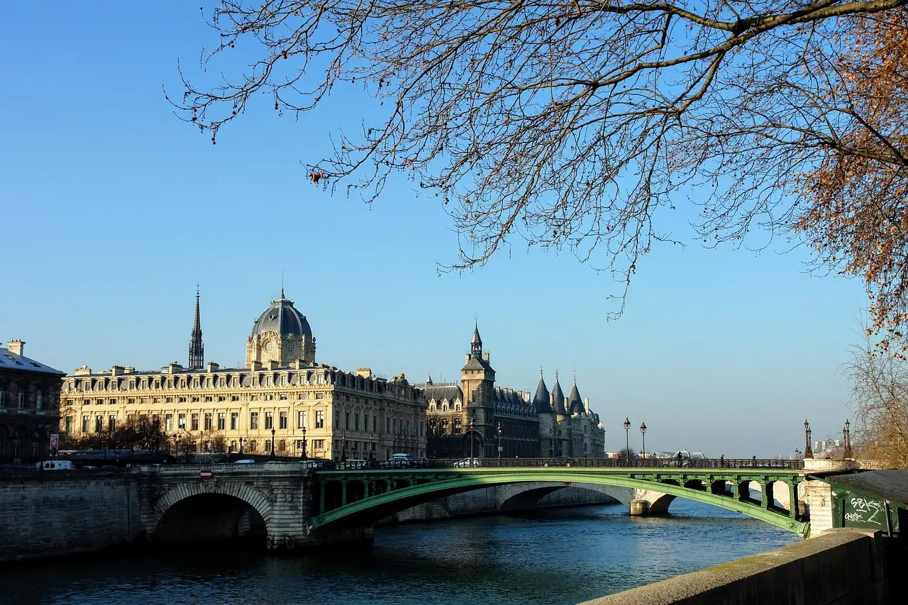 The Conciergerie beyond a Seine bridge on a sunny day