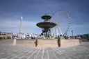 A fountain on Place de la Concorde with the obelisk and a Ferris wheel behind
