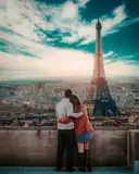 A couple arm in arm at a viewpoint above Paris, facing the Eiffel Tower
