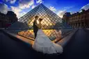 A couple posing in front of the Louvre pyramid at sunset