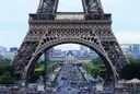 The Eiffel Tower's first-level arch framing the Champ de Mars and the crowds beneath it