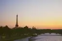 The Eiffel Tower above the Seine at sunset, with a boat on the river