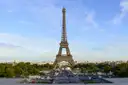 The Eiffel Tower seen from the Trocadéro side under a pale blue sky