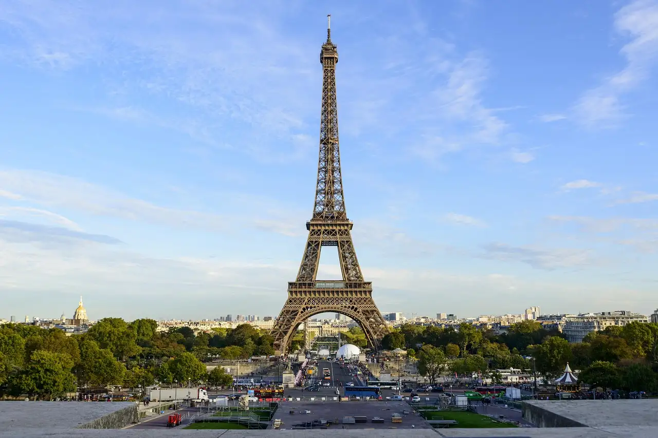 The Eiffel Tower seen from the Trocadéro side under a pale blue sky
