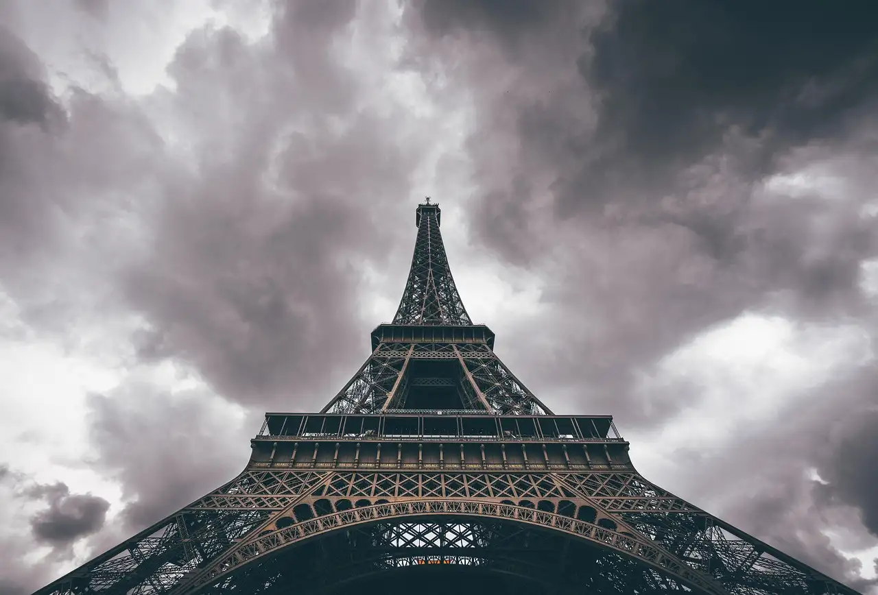 Looking up at the Eiffel Tower from below under dark storm clouds