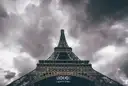Looking up at the Eiffel Tower from below under dark storm clouds