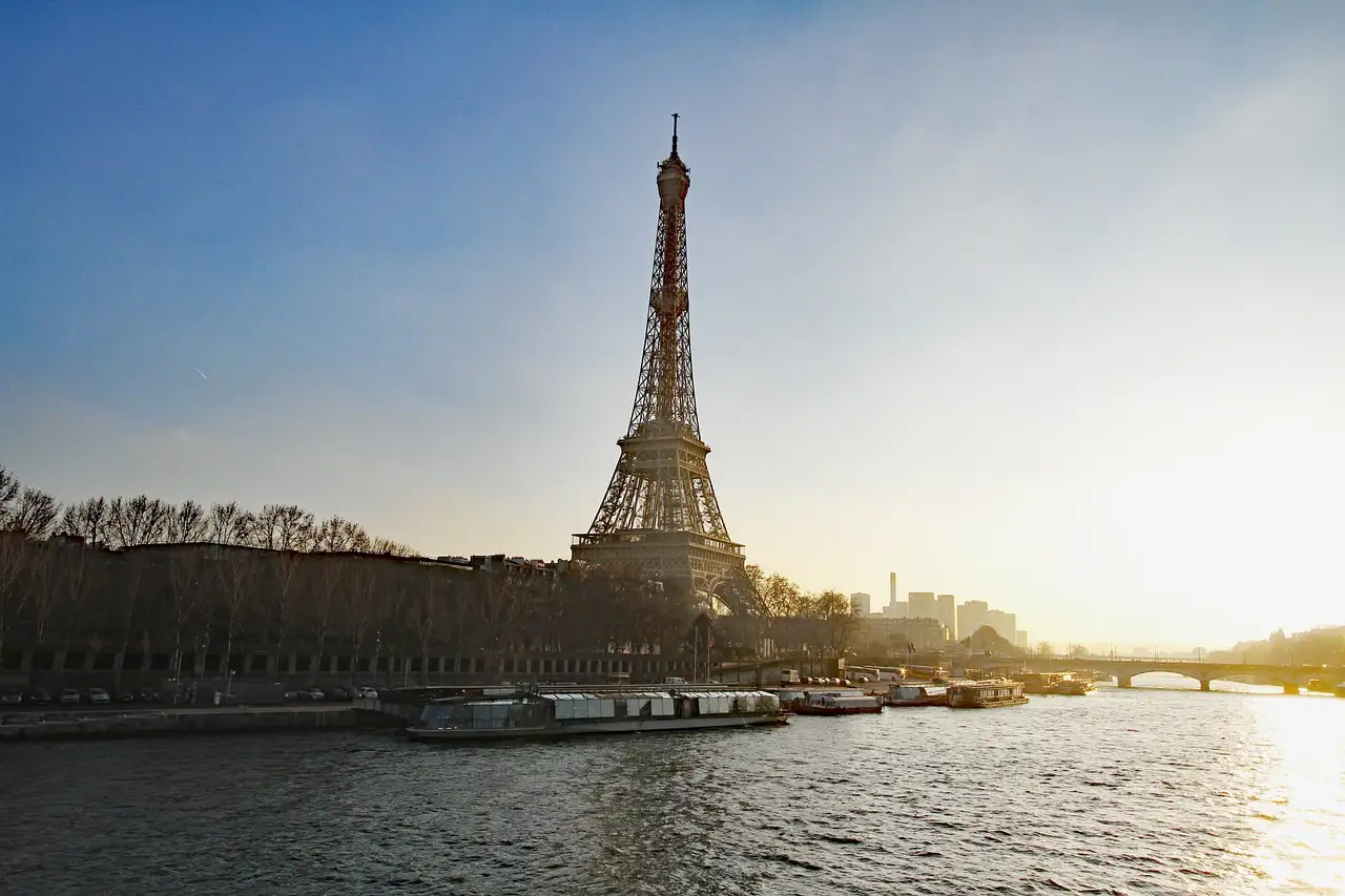 The Eiffel Tower above the Seine with boats along the bank
