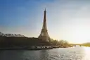 The Eiffel Tower above the Seine with boats along the bank
