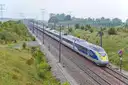 A blue and grey high-speed Eurostar train running along a track through green countryside