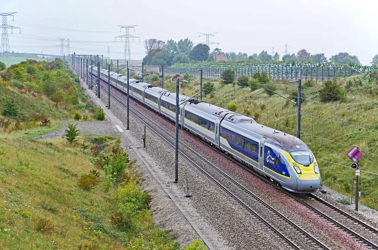 A blue and grey high-speed Eurostar train running along a track through green countryside