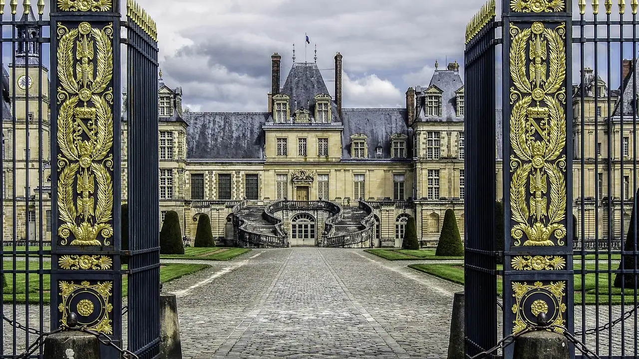 The Château de Fontainebleau through its open gilded gates, across the cobbled courtyard
