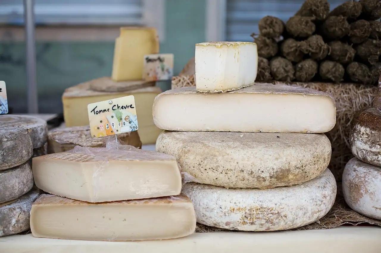 Wheels and blocks of French cheese stacked on a cheese counter