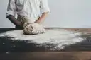 Hands kneading bread dough on a floured table