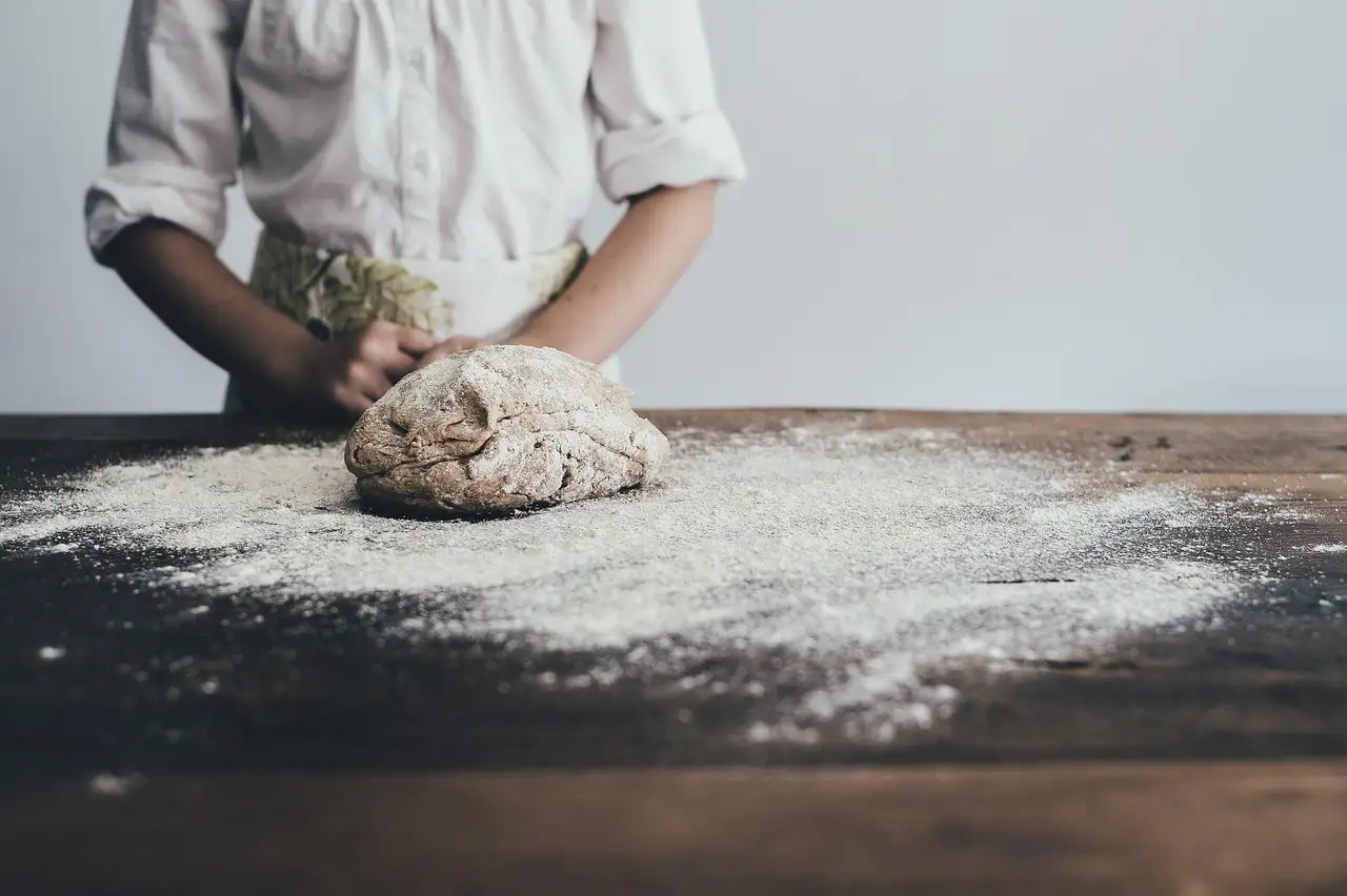 Hands kneading bread dough on a floured table