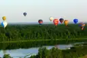 Colourful hot air balloons drifting over a forest and lake in France