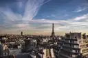 Paris rooftops with the Eiffel Tower and Montparnasse tower under a streaky evening sky