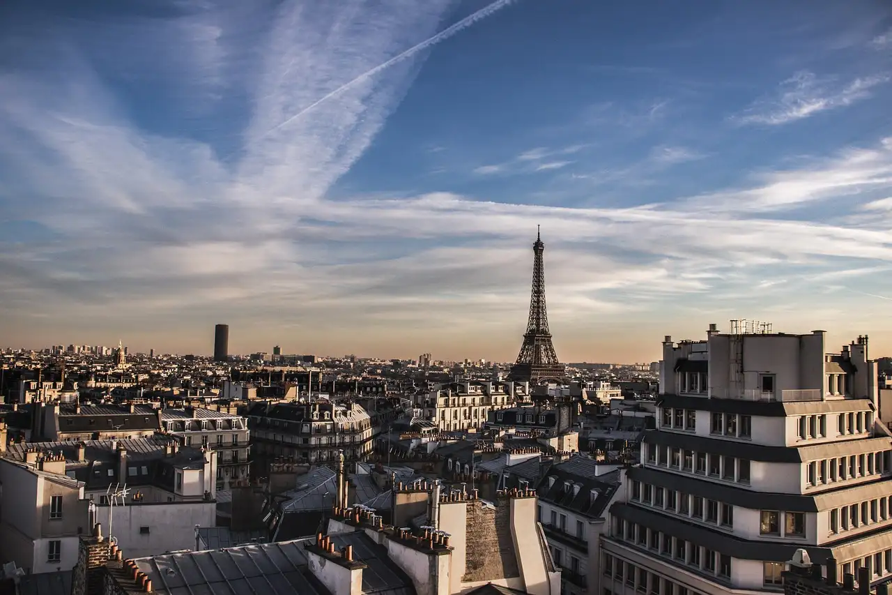 Paris rooftops with the Eiffel Tower and Montparnasse tower under a streaky evening sky