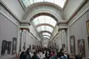 The Grande Galerie of the Louvre lined with paintings, with visitors walking through