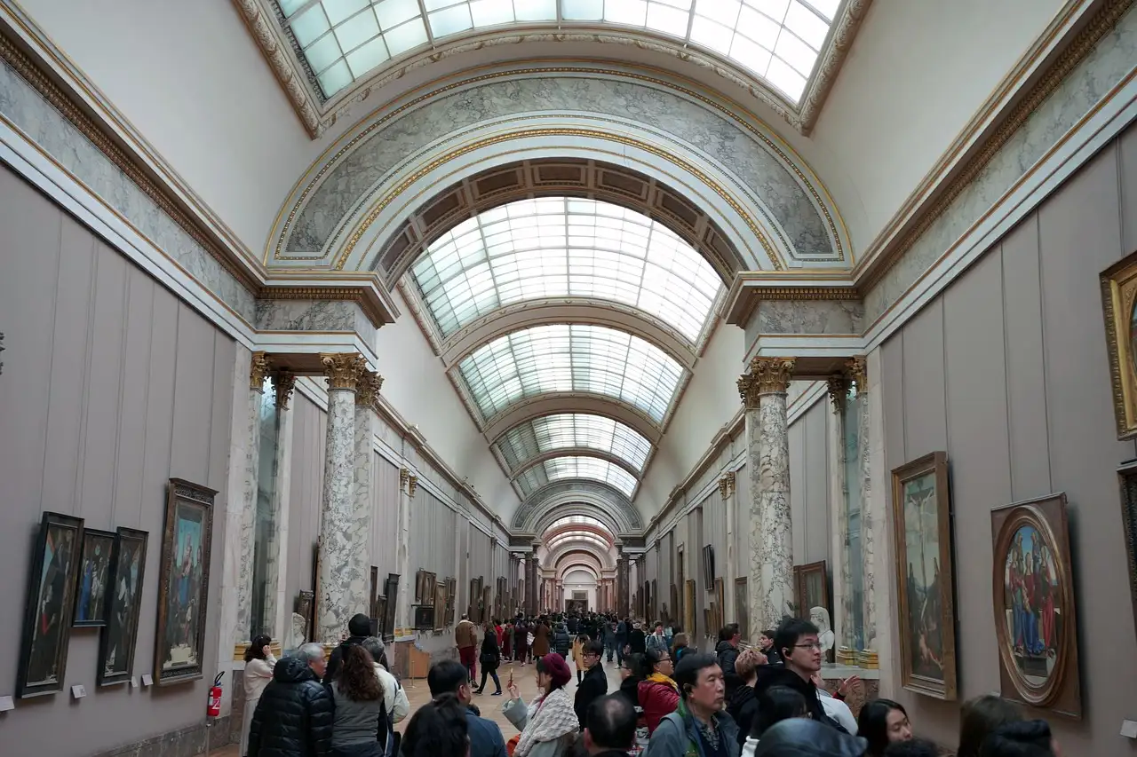 The Grande Galerie of the Louvre lined with paintings, with visitors walking through