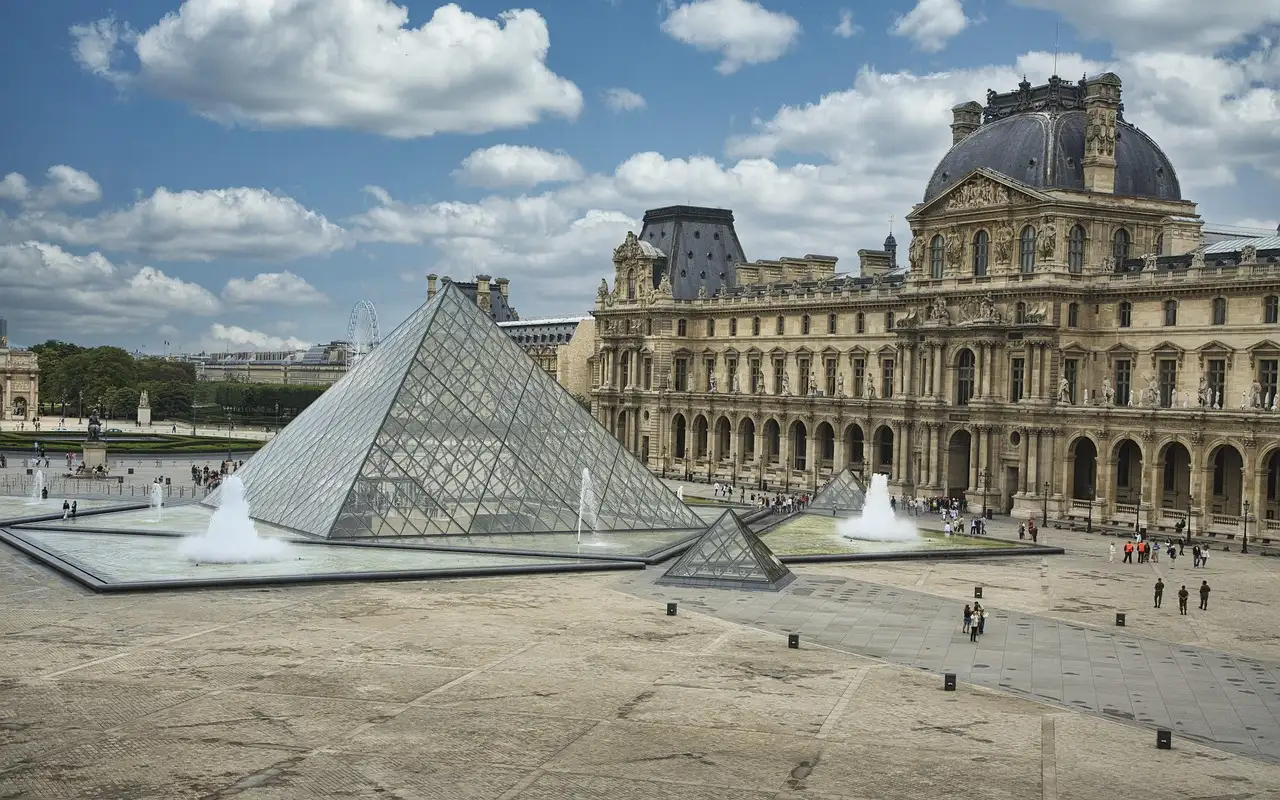 The Louvre glass pyramid and palace courtyard on a sunny day