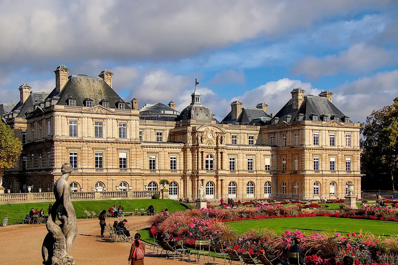 The Luxembourg Palace behind flower beds and a statue in the Luxembourg Gardens