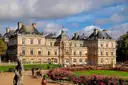 The Luxembourg Palace behind flower beds and a statue in the Luxembourg Gardens