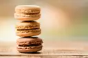 A stack of three macarons on a wooden table