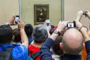 Visitors raising phones to photograph the Mona Lisa in the Louvre