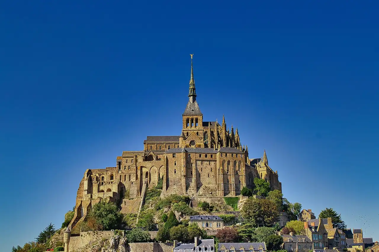 The abbey of Mont-Saint-Michel and its spire against a deep blue sky