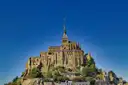 The abbey of Mont-Saint-Michel and its spire against a deep blue sky