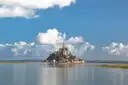 Mont-Saint-Michel seen across calm water under a blue sky