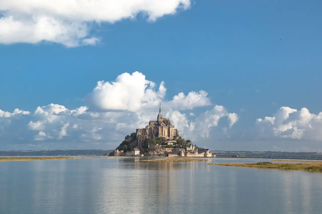 Mont-Saint-Michel seen across calm water under a blue sky