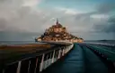 The footbridge leading across the bay to Mont-Saint-Michel under heavy clouds